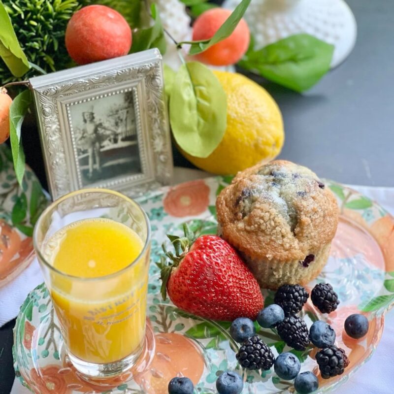 fresh fruit with glass of orange juice on floral plate for Mother's Day celebration.