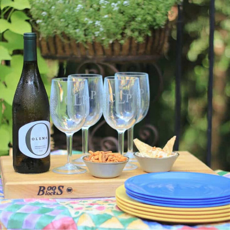 summer picnic with wine glasses, bottle of wine, plates, and snacks