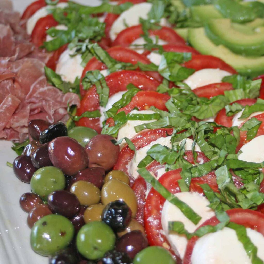 Beyond the caprices salad with olives, roasted peppers, avocado, prosciutto
