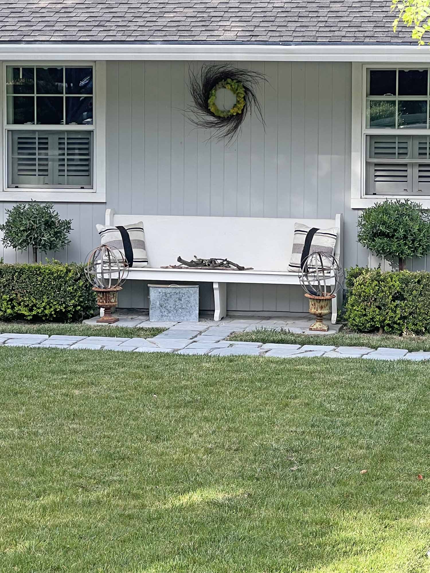 church pew bench with olive tree topiaries and garden orbs on cast iron urns