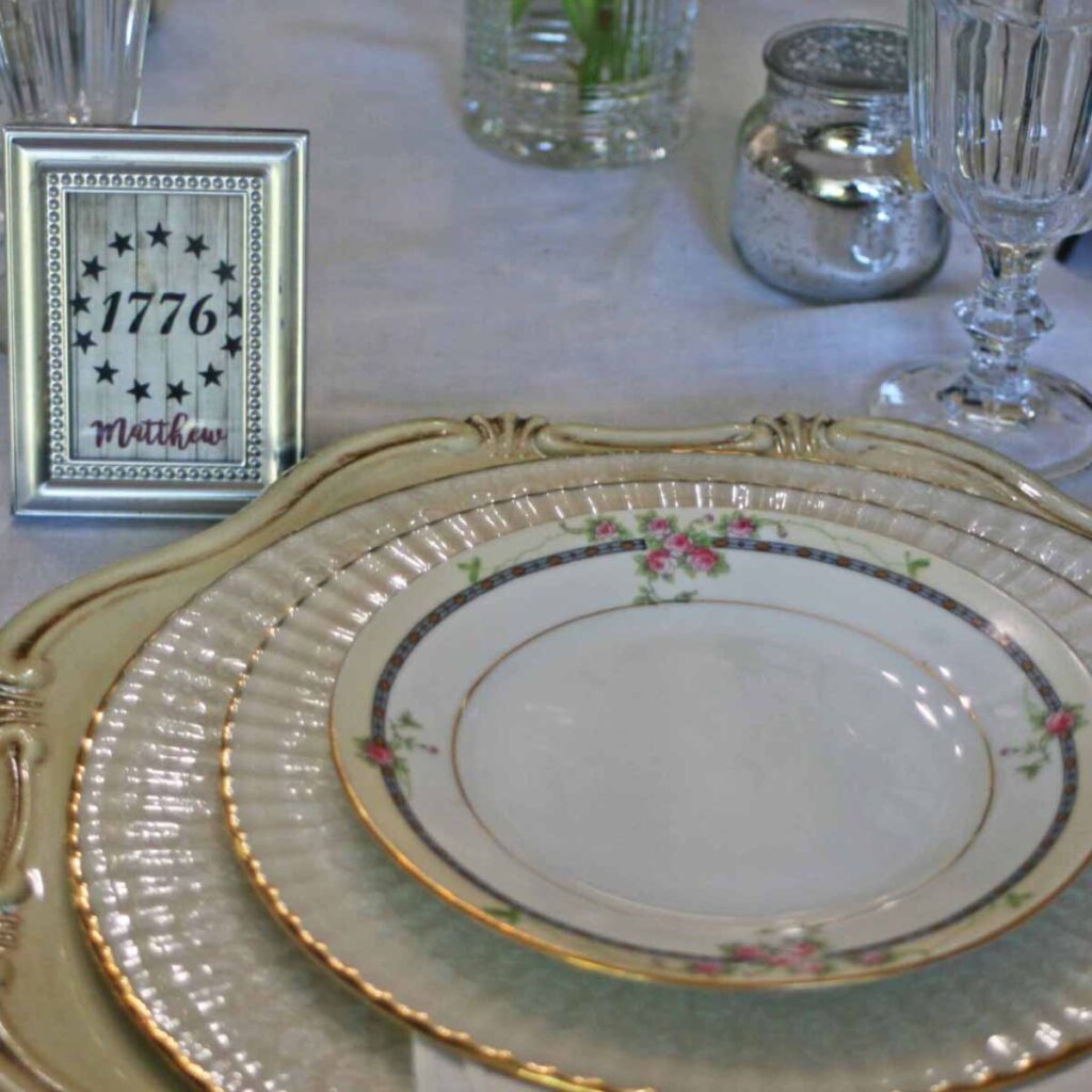 Patriotic tablescape with thrifted dishes plate stack with framed place card holder