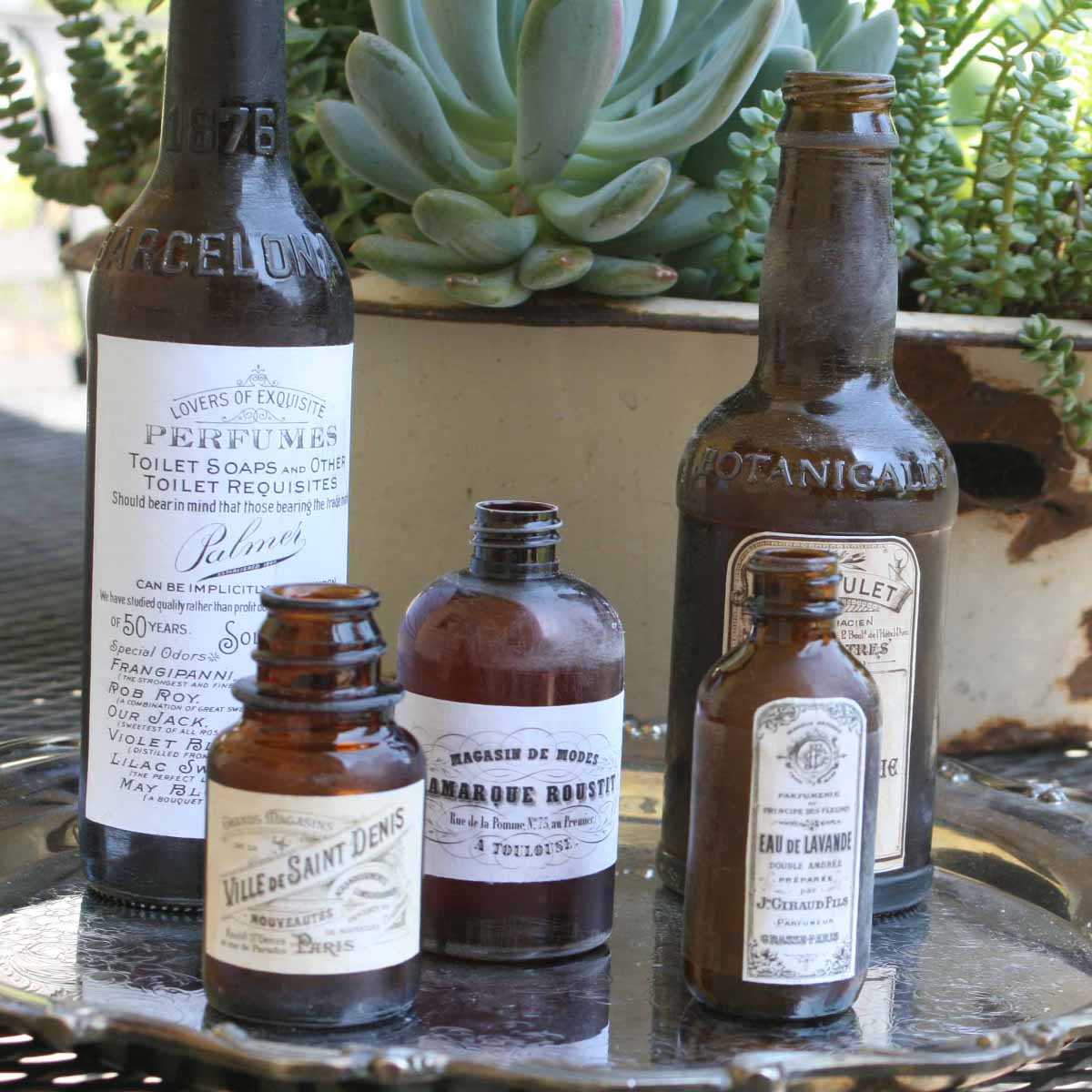 brown bottles recycled with vintage French label graphics soon silver tray on back patio table