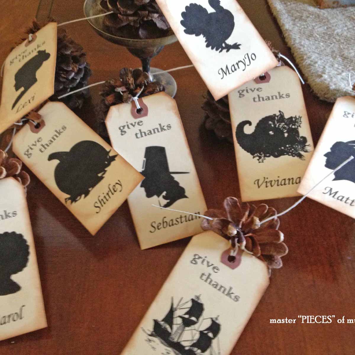 Thanksgiving place cards DIY with silhouettes and pinecones grouped together on dining room table