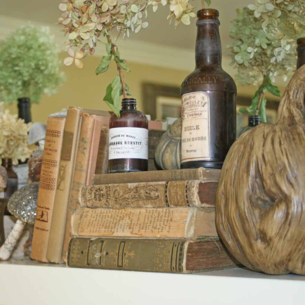 woodland themed fall mantel styling with vintage books, brown bottles, wooden pumpkins and hydrangeas