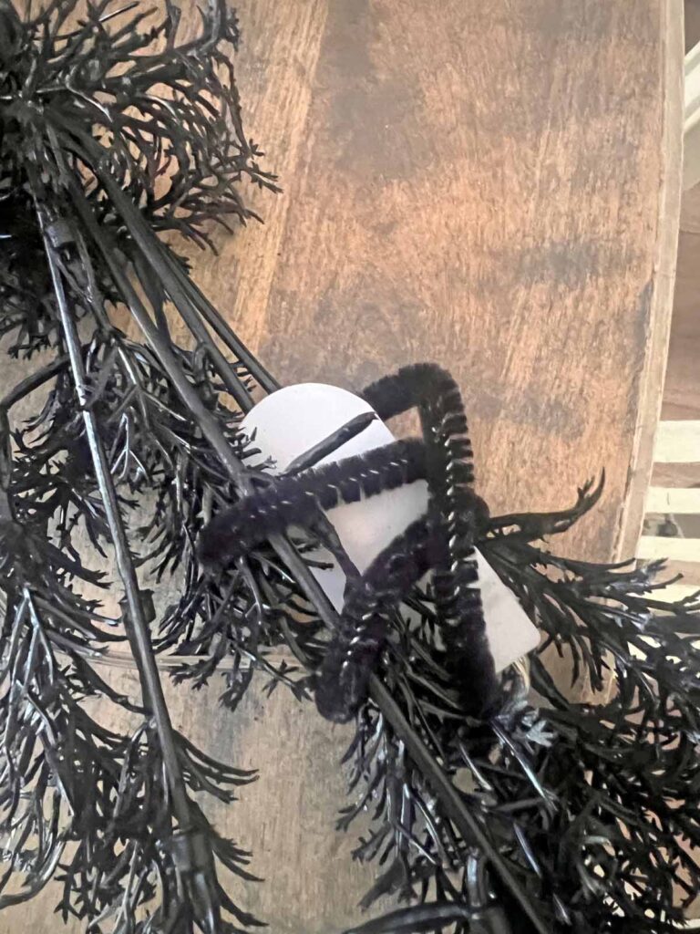 Another Anthropologie Dupe: Cascading black boughs Halloween garland DIY attaching light battery pack with pipe cleaners