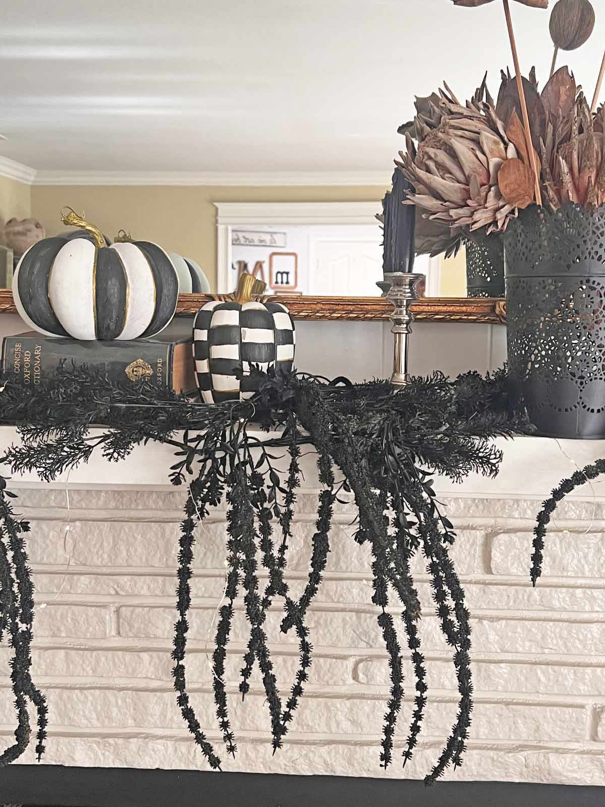 Another Anthropologie Dupe: Cascading black boughs Halloween garland DIY styled with MacKenzie Child's pumpkins, moody florals, candlestick