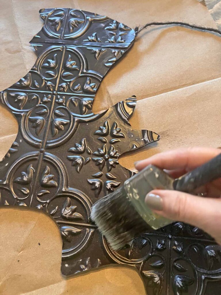 Halloween Decor: Faux tin tile bat DIY dusting sanding off with paint brush